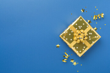 Golden gift boxes and confetti on color background, top view