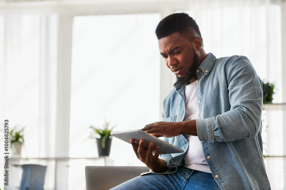 Poster Concerned african american employee browsing data on digital tablet, can not find necessary information before presentation.