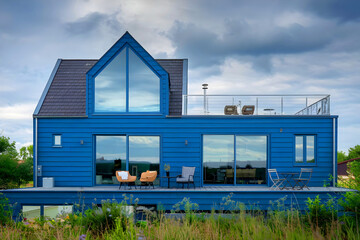 Obraz premium A blue house with solar panels and a rooftop patio with sliding doors.