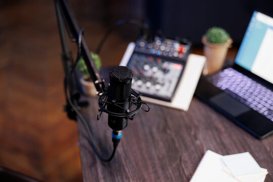 Home recording setup for a radio show or podcast, featuring a microphone, laptop, and sound equipment. Top view of desk containing professional mic and sound mixer, ideal for home studio.