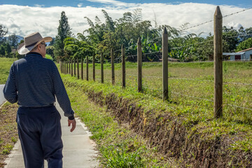 Senior hispanic landowner walking next to his farm in Colombia