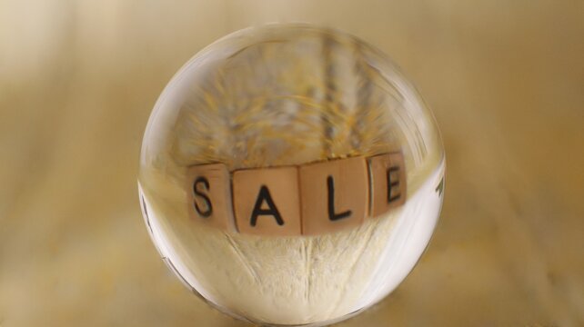 Close-up of a glass ball that reflects a yellow structure with the word Sale