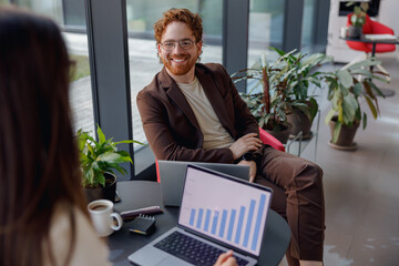 A collaborative business meeting taking place in a stylish and modern office space featuring charts...