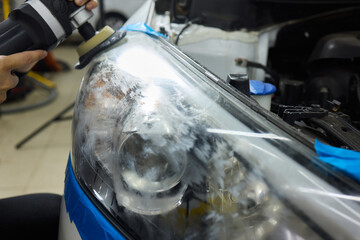 Person using a machine to polish automotive lighting on a car headlight