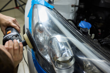 Person using a machine to polish automotive lighting on a car headlight