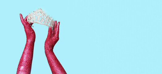Female hands covered with glitter holding beautiful tiara on blue background with space for text © Pixel-Shot