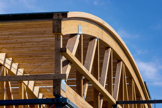 Construction detail of curved roof laminated timber beams or joists against a blue sky