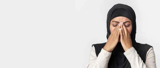 Upset black muslim woman in hijab covering face with hands, can't believe news, depressed and in...