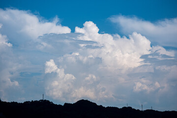 青空に浮かぶ入道雲と山のシルエット