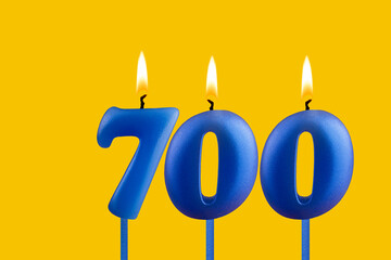 Blue candle number 700 - Birthday on yellow background