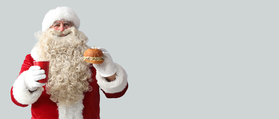 Santa Claus with cup of tea and tasty burger on white background