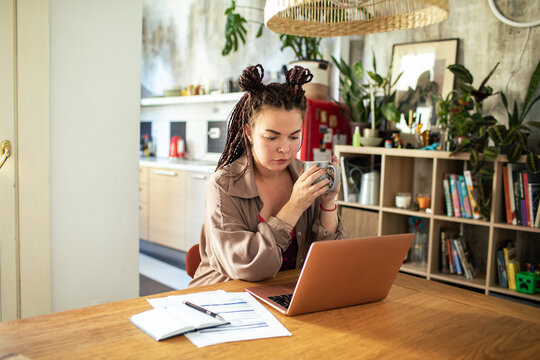 Young hipster woman working on laptop from home