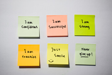 I am confident, I am strong, never give up with smile emoticon on sticky notes. Motivational for...