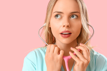 Female medical intern with stethoscope on pink background, closeup