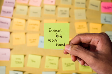 Hand hold sticky notes with words Dream Big, Work Hard. Motivational words for personal development, inspirational handwriting. Sticky notes background