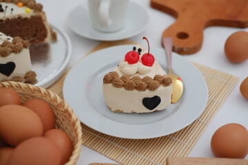A piece of cake on a white plate with a spoon on a bamboo mat. beautiful decoration