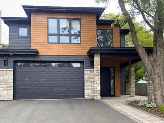 A street view of a modern suburban-style house. There's a patio, the exterior walls are faux wood...