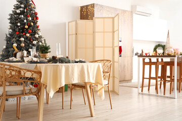 Interior of modern dining room with Christmas tree and festive table setting