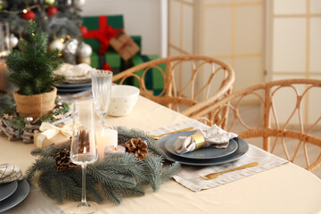 Christmas table setting with wreathes, burning candles and pine cones