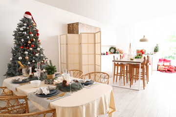 Interior of modern dining room with Christmas tree and festive table setting