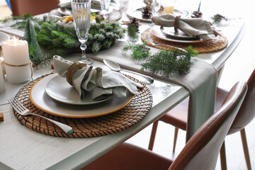 Christmas table setting with folded napkins, plates, cutlery and fir branches