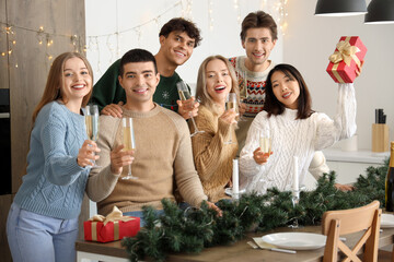 Group of young people with champagne celebrating Christmas in kitchen