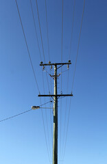 Utility pole and power lines set against a clear blue sky