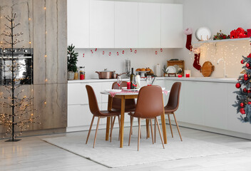 Interior of modern kitchen with festive table setting, Christmas tree and decor