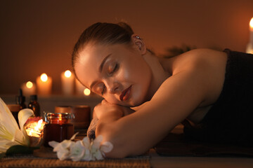 Beautiful young woman relaxing in dark spa salon, closeup