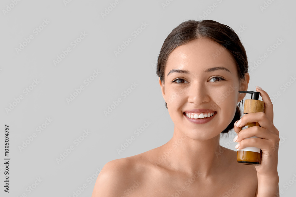 Poster Beautiful Asian woman with bottle of cream on light background, closeup