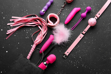 Shopping bag with different sex toys on grunge black background
