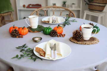 Autumn table setting with pumpkins, burning candles and leaves