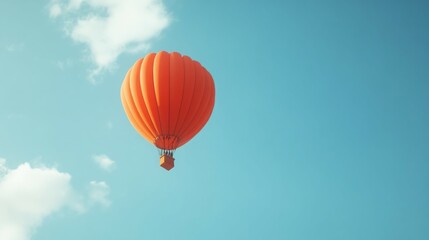 Fototapeta premium A bright orange hot air balloon drifts through a clear blue sky.