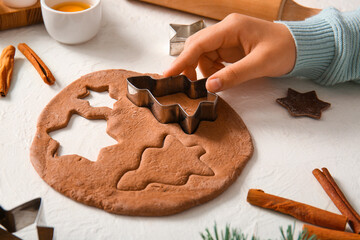 Woman preparing tasty Christmas gingerbread cookies on grunge white background