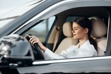 Woman driving car, hand on steering wheel, looking at camera