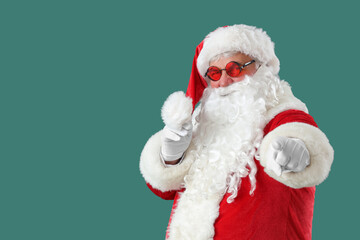 Cool Santa Claus pointing at viewer on green background