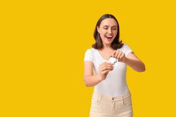 Beautiful young woman with open condom on yellow background. Safe sex concept