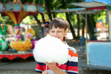 Portrait of little boy eating sweet cotton candy in park