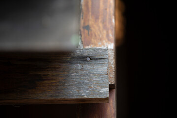 Old wooden door with rusty nail in the dark. Selective focus.