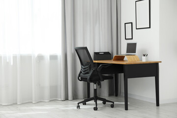 Black chair, laptop and desk in office