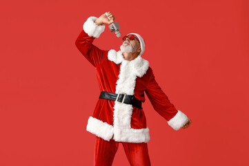 Santa Claus in sunglasses with microphone singing on red background