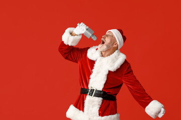 Santa Claus in glasses with microphone singing on red background