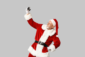 Santa Claus in glasses with camera taking photo on grey background