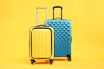 Two different bright suitcases on yellow background