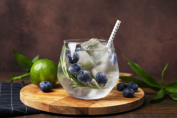 Refreshing water with blueberries and rosemary in glass on wooden table
