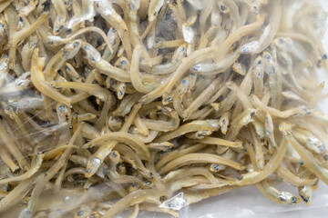 This close-up image showcases a textured mound of dried anchovies, their silvery bodies intertwined and glistening with natural oils.