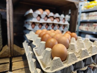 Close up shot of stacked cardboard egg tray boxes with fresh eggs lie on a supermarket shelf to be sold