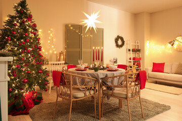 Interior of festive room with Christmas tree, decorations and served dining table at evening