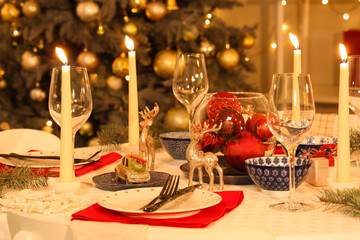 Festive table setting with burning candles and Christmas decorations at evening, closeup