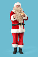 Santa Claus with tasty burger showing thumb-up on blue background
